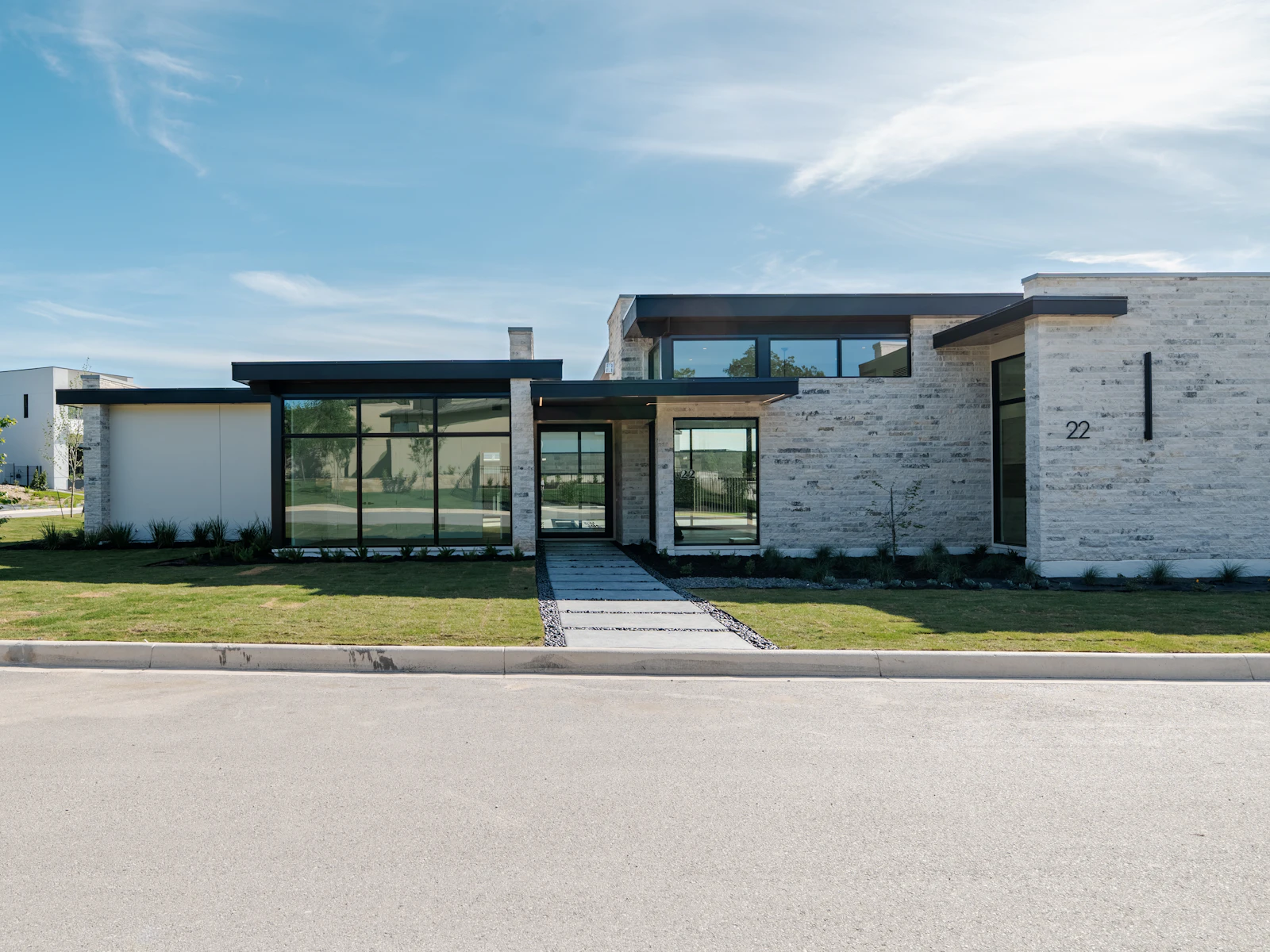 Illustrative photo of a modern house with large windows and a green lawn