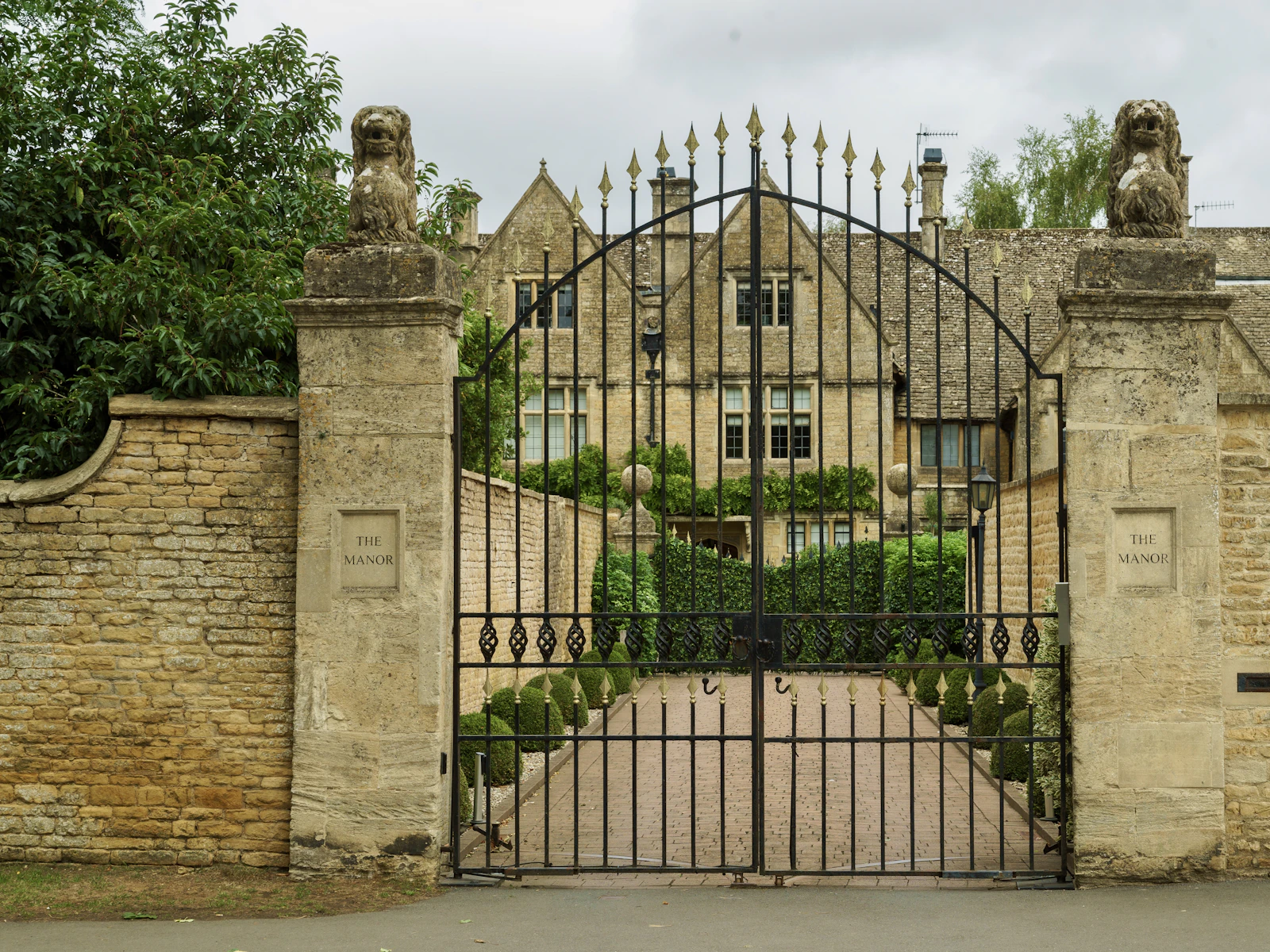 Illustrative photo of ornate metal gate guarding a large stone manor house