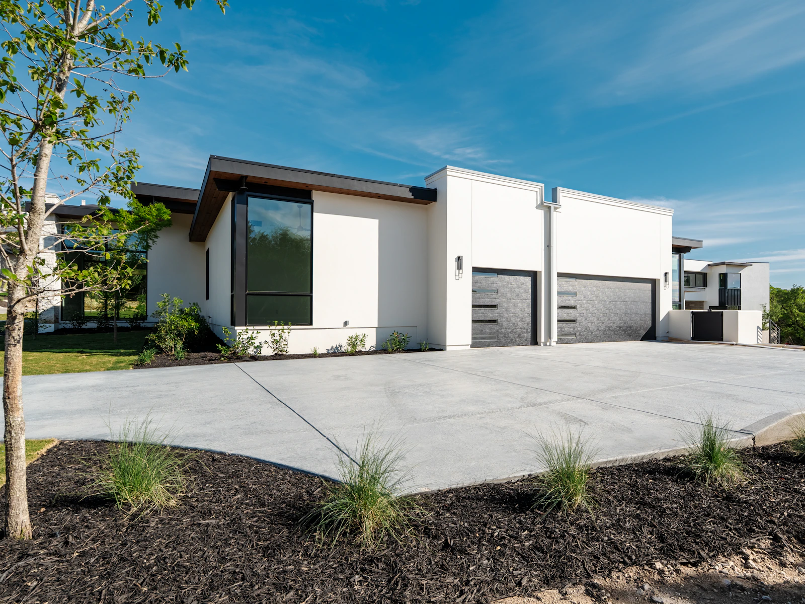 Illustrative photo of a modern white house, two garage doors and a concrete driveway