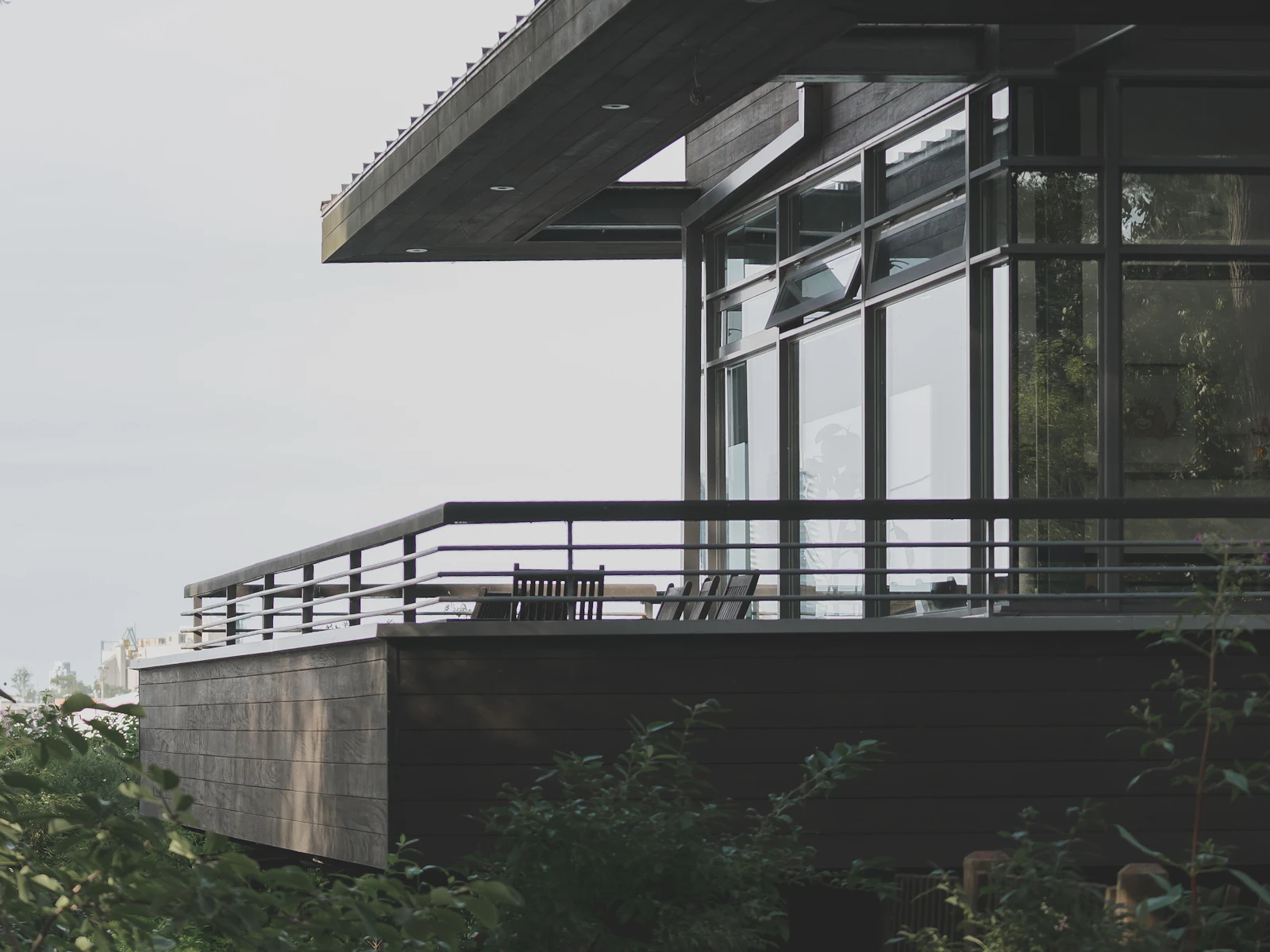 Illustrative photo of a black modern home with broad glass windows and a terrace