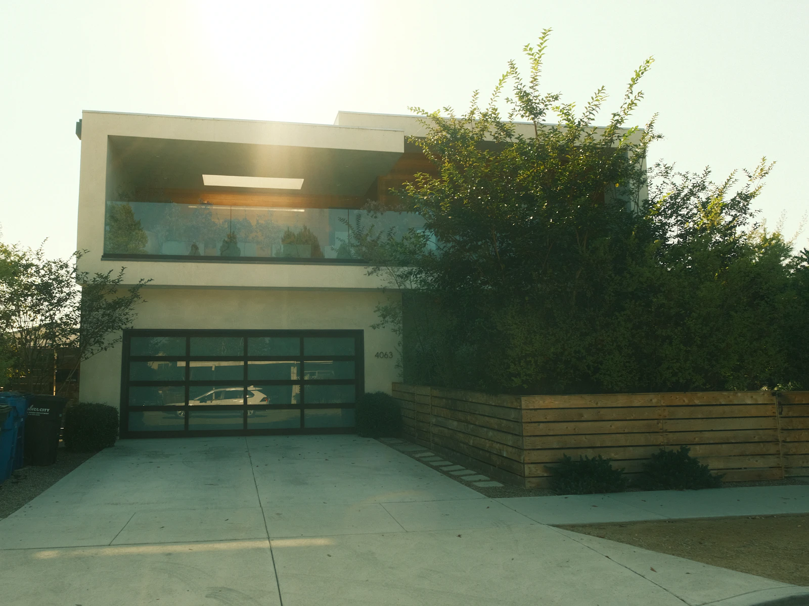 Illustrative photo of a modern home with a concrete driveway and glass garage door