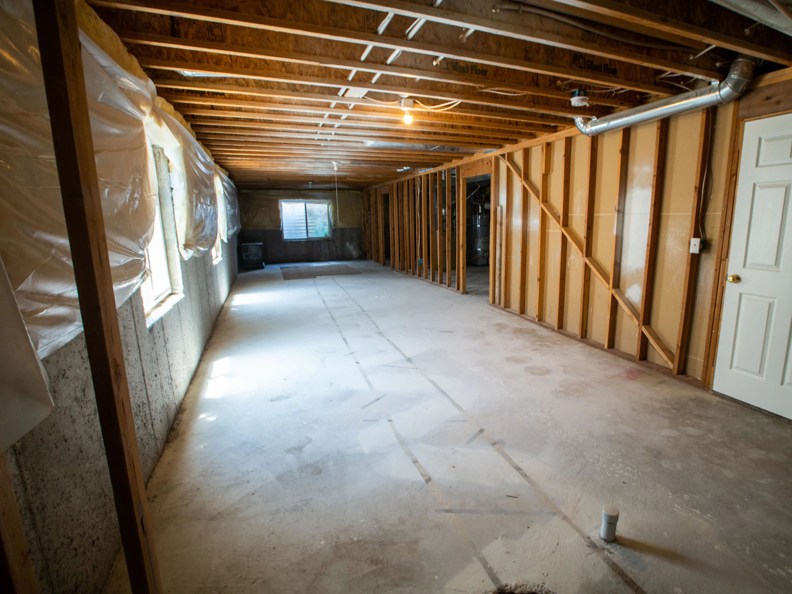 Illustrative photo of an unfinished basement with exposed framing, concrete floor and mechanical ductwork