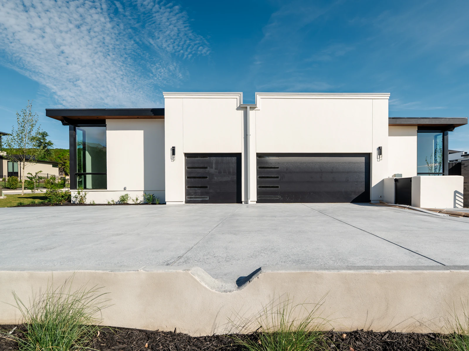 Illustrative photo of two contemporary white homes with black garage doors