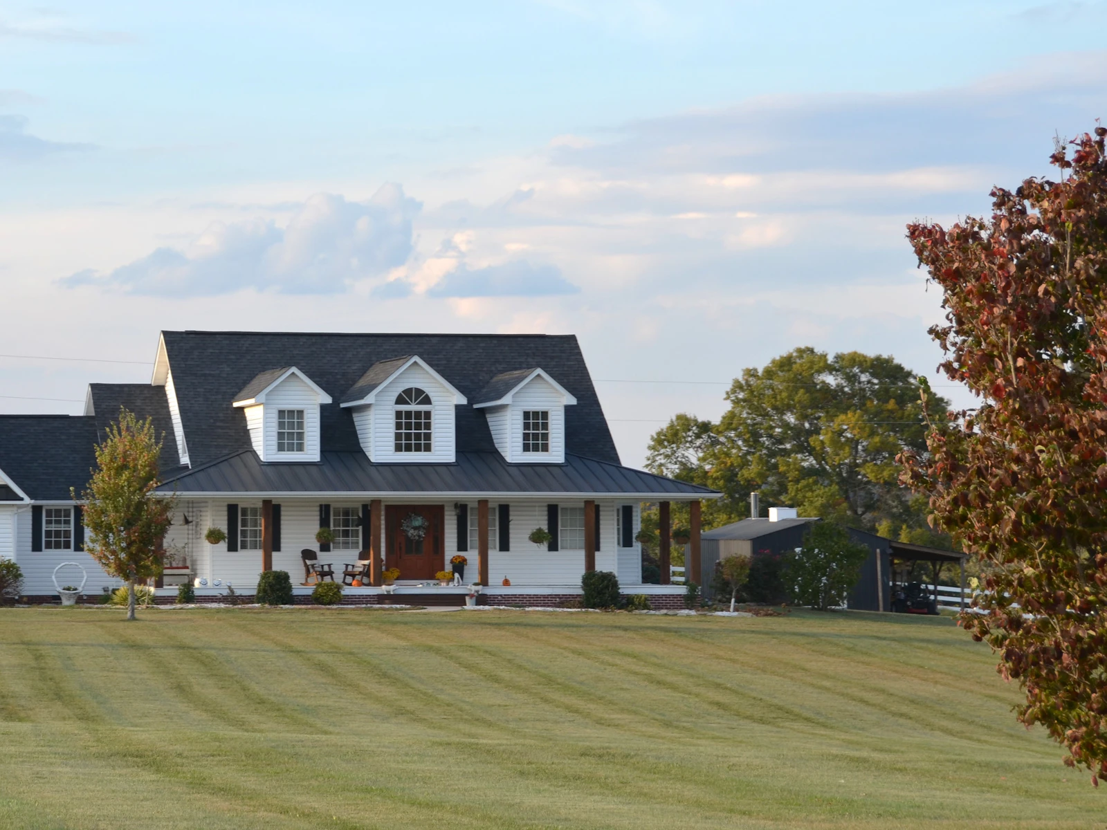 Illustrative photo of a large white farmhouse with a wrap-around porch