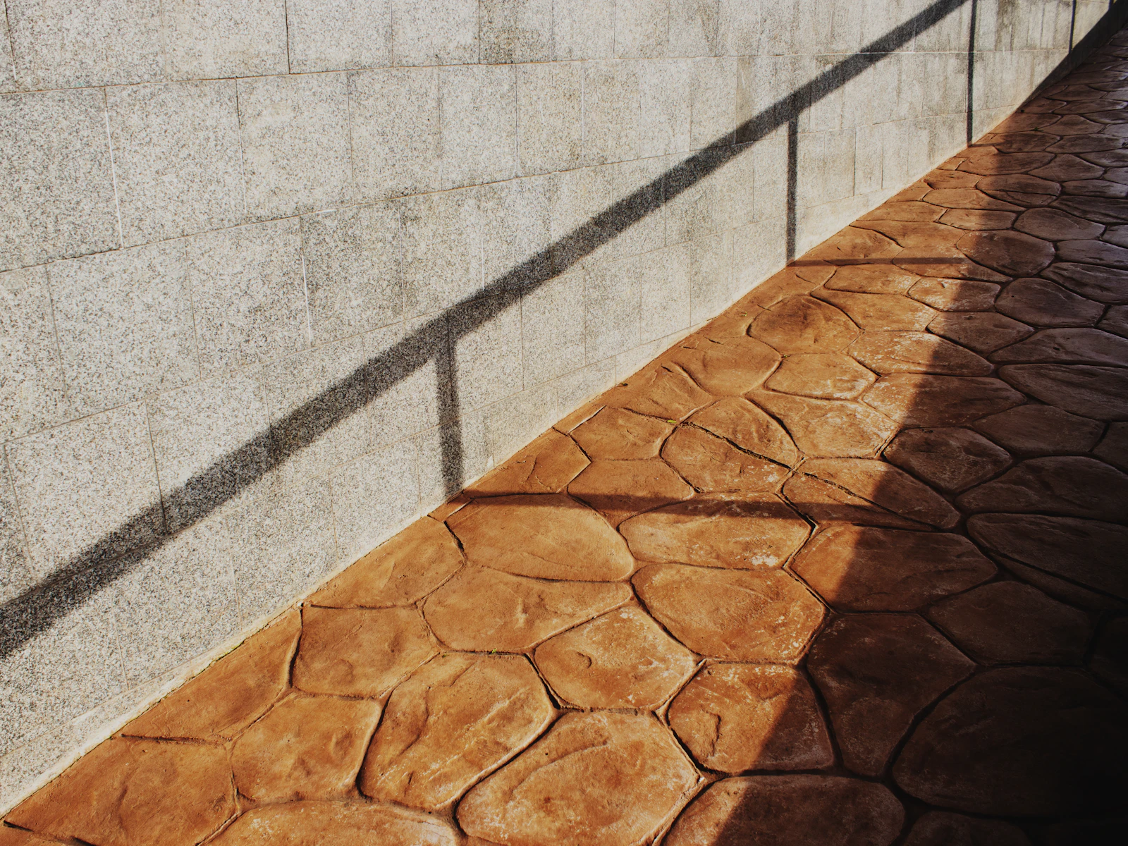 Illustrative photo of shadows cast on a textured wall and patterned walkway