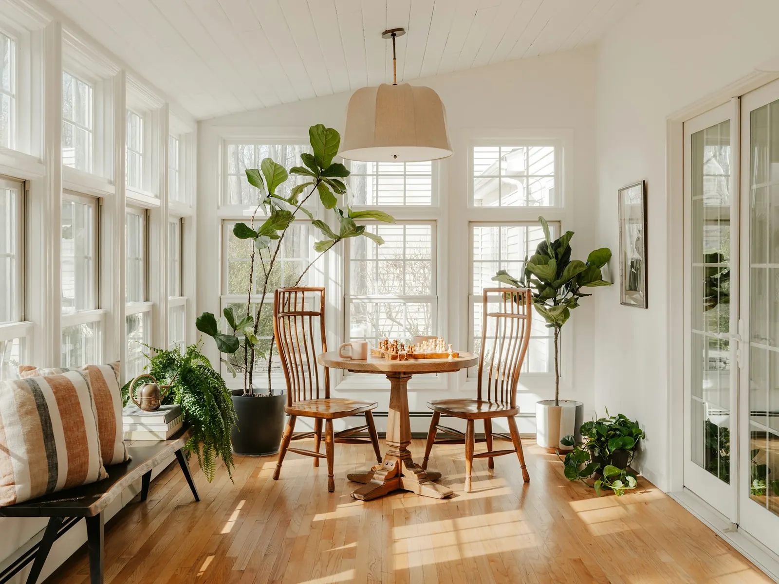 Illustrative photo of a bright home addition with large windows, plants and a small table