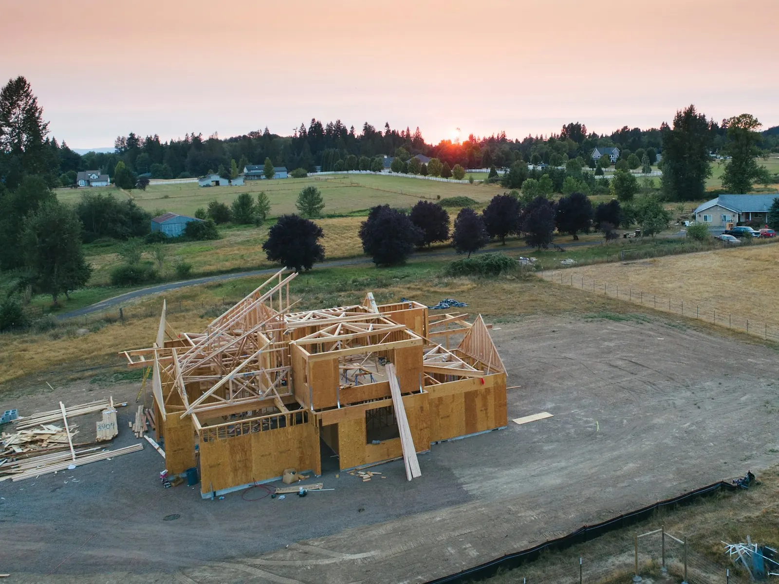 Illustrative photo of a new house frame going up on an open lot at sunset