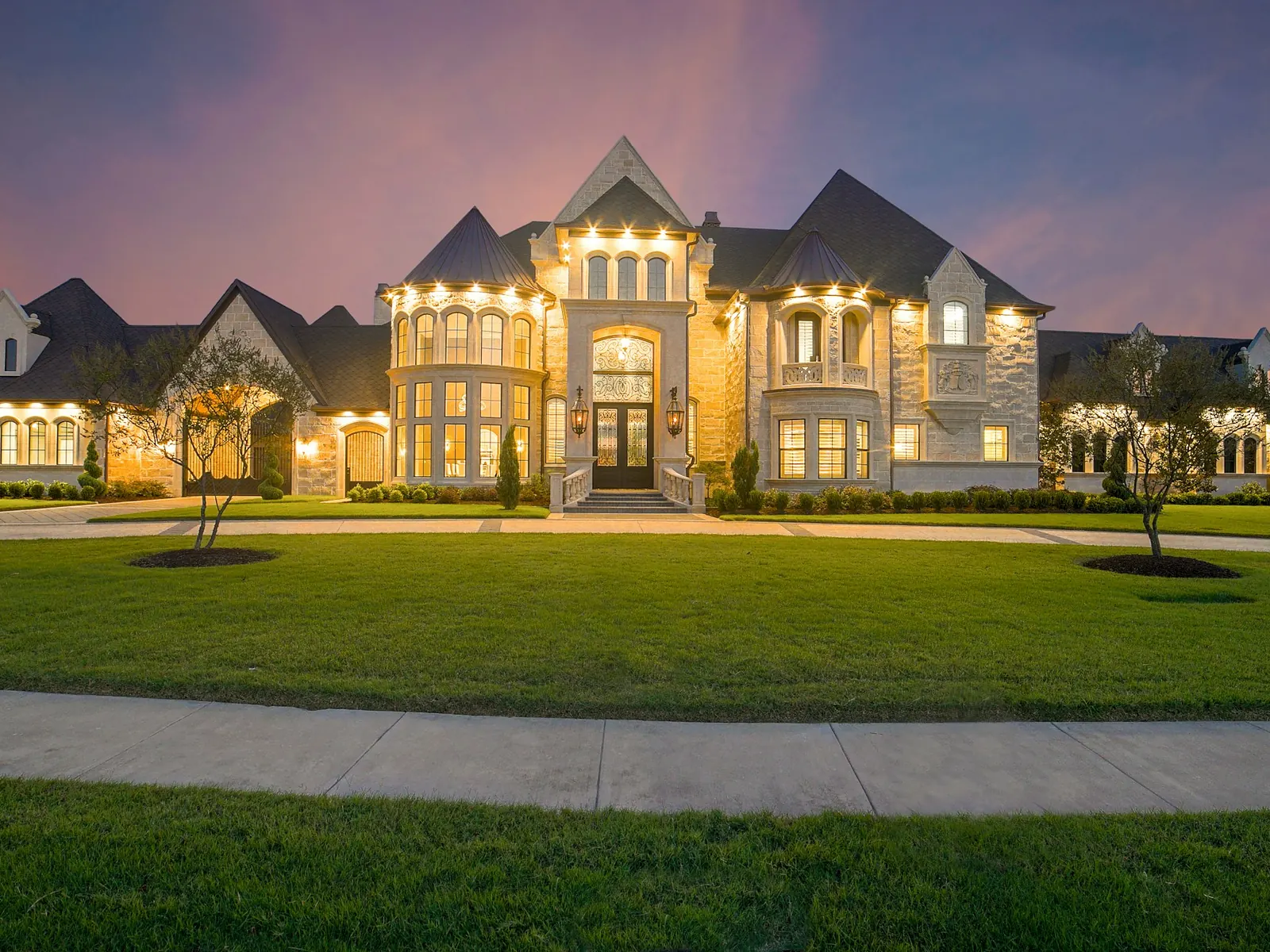 Illustrative photo of a large stone home with its windows lit at dusk