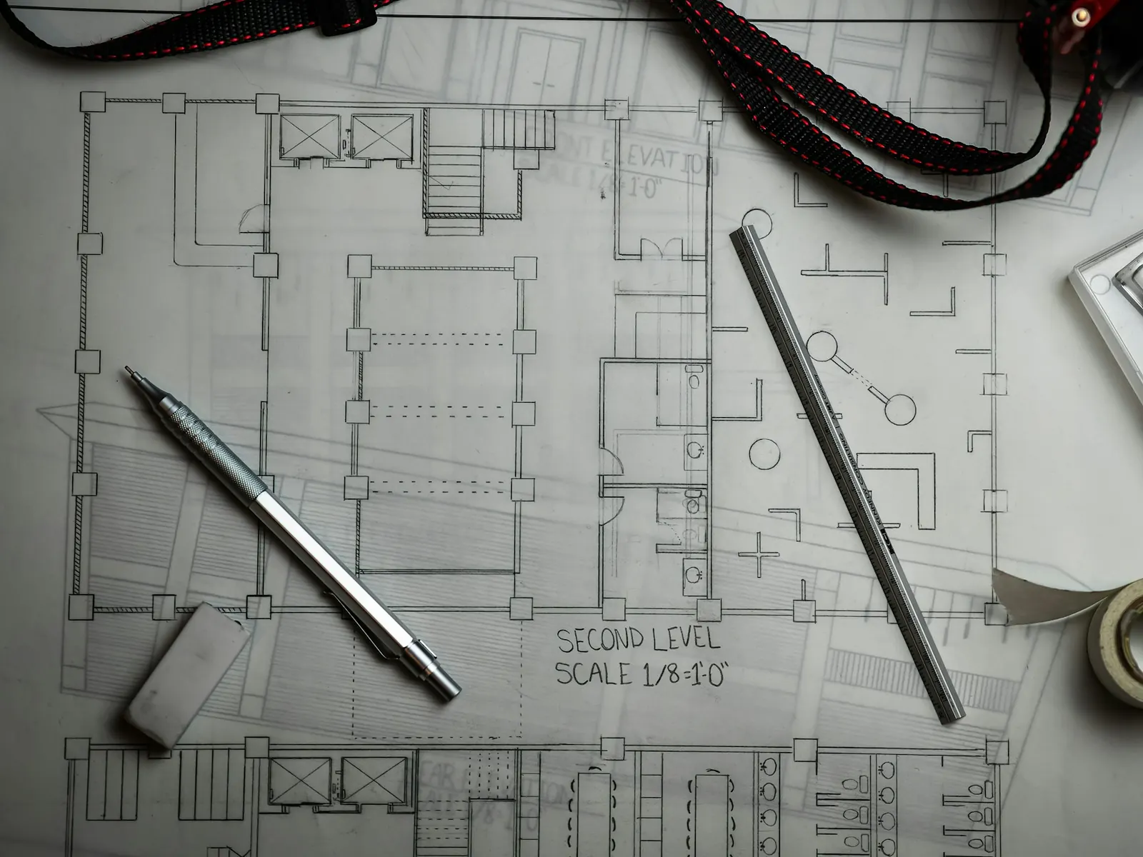 Illustrative photo of architectural floor plans with drafting pens and tape